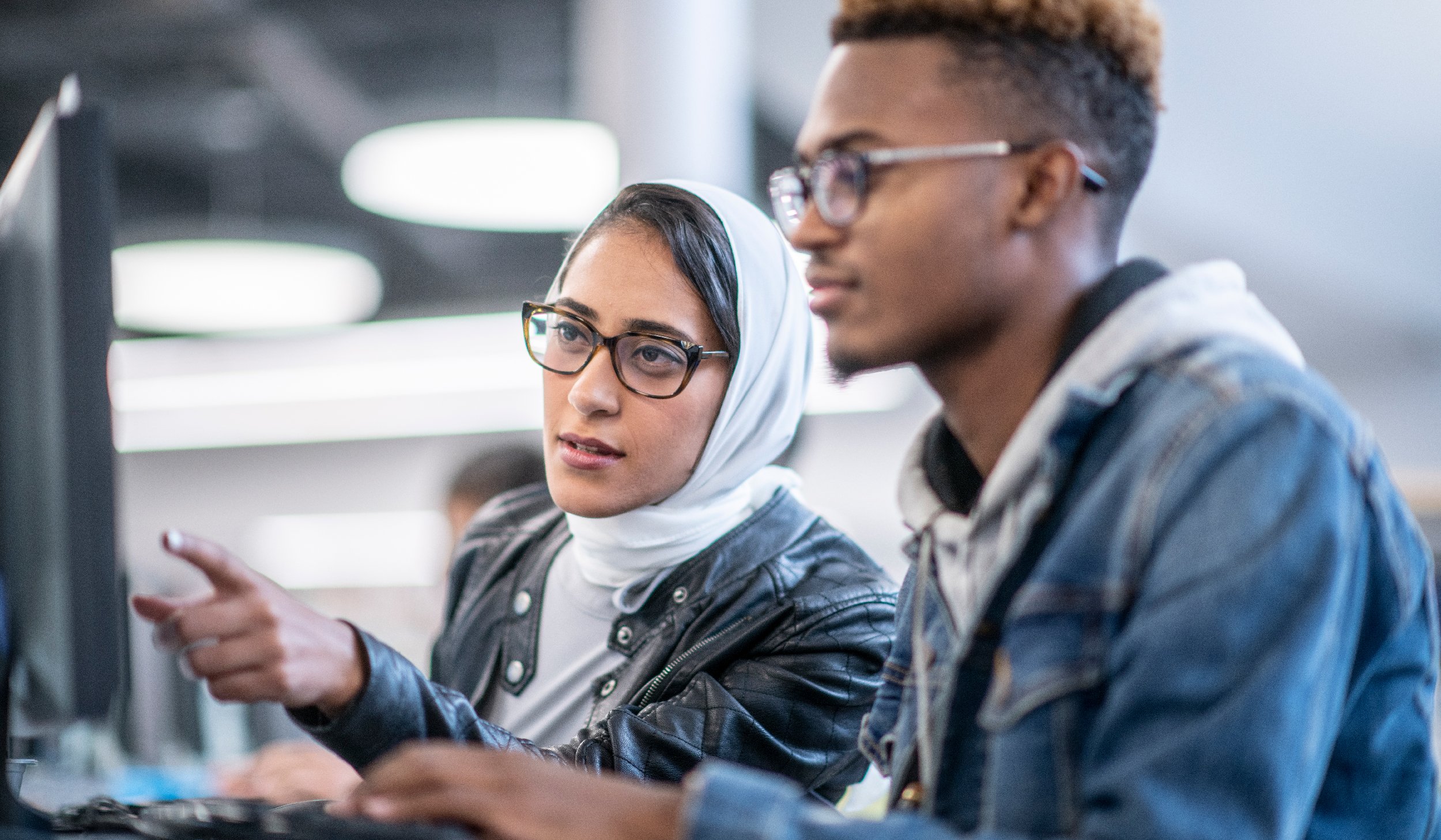 Woman and man working together, looking at screen